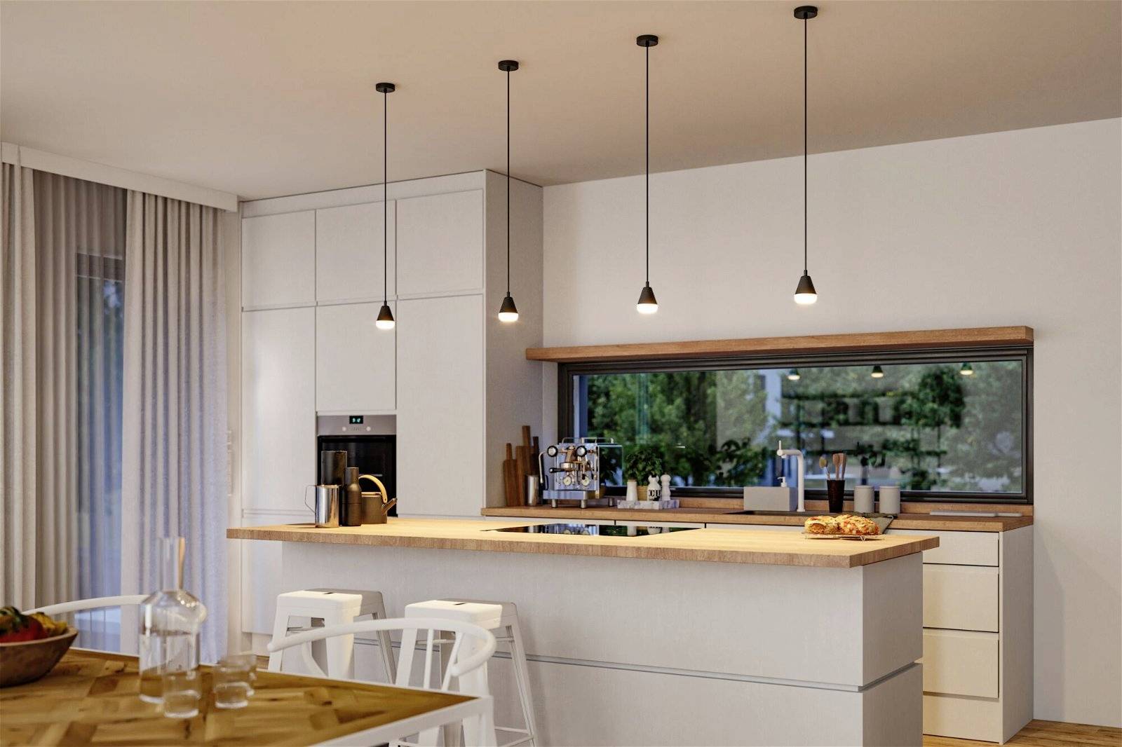 Moderná kuchyňa s kuchynským ostrovčekom, závesnými lampami a veľkými oknami. Jedálenský stôl s karafou v popredí, kuchynské spotrebiče v pozadí.