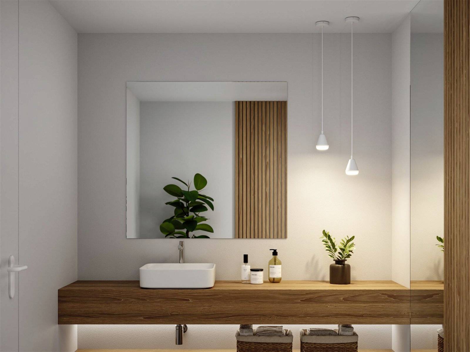 Moderná kúpeľňa s dreveným umývadlovým stolíkom, oválnym umývadlom, veľkým zrkadlom a minimalistickými rastlinnými akcentmi.
