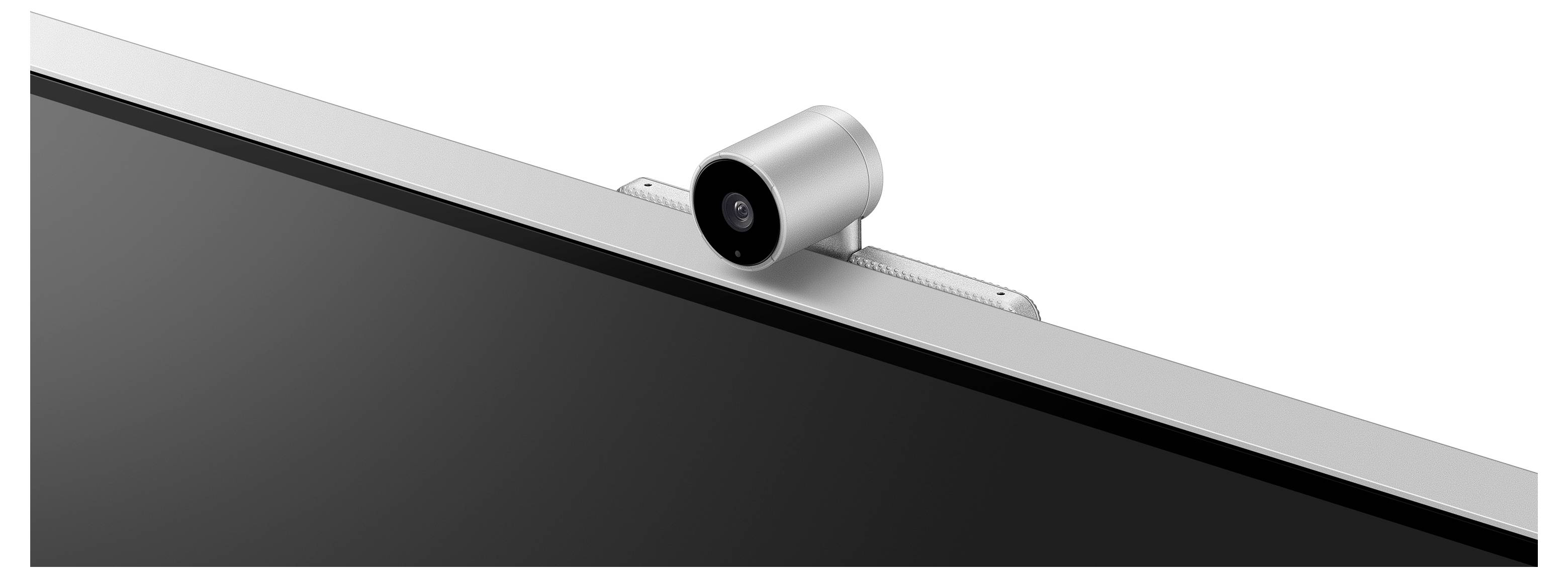 Kamera namontovaná nad počítačovým monitorom. Kamera je striebornej farby a valcovitého tvaru.