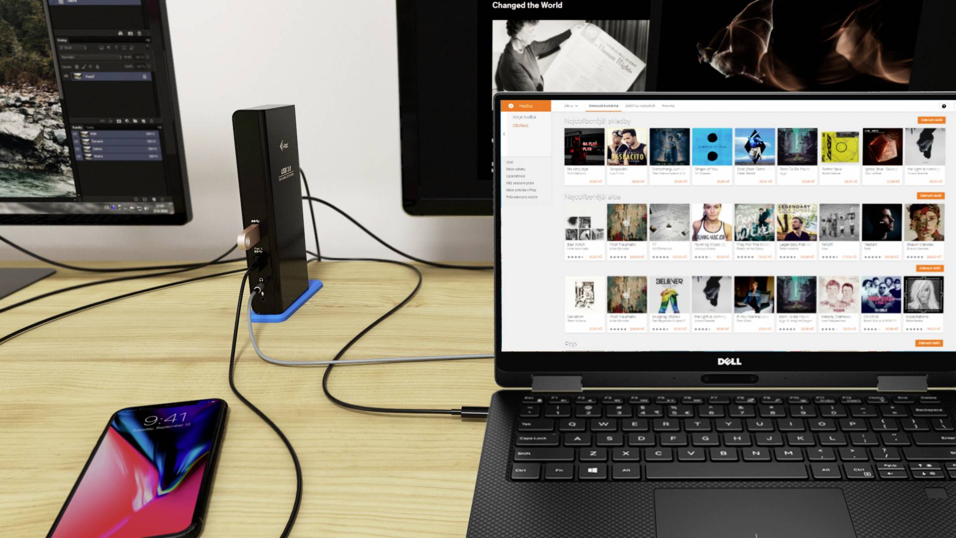 Písací stôl s laptopom Dell, smartfónom a dvoma monitormi. Na jednom monitore je otvorený softvér hudobnej knižnice.