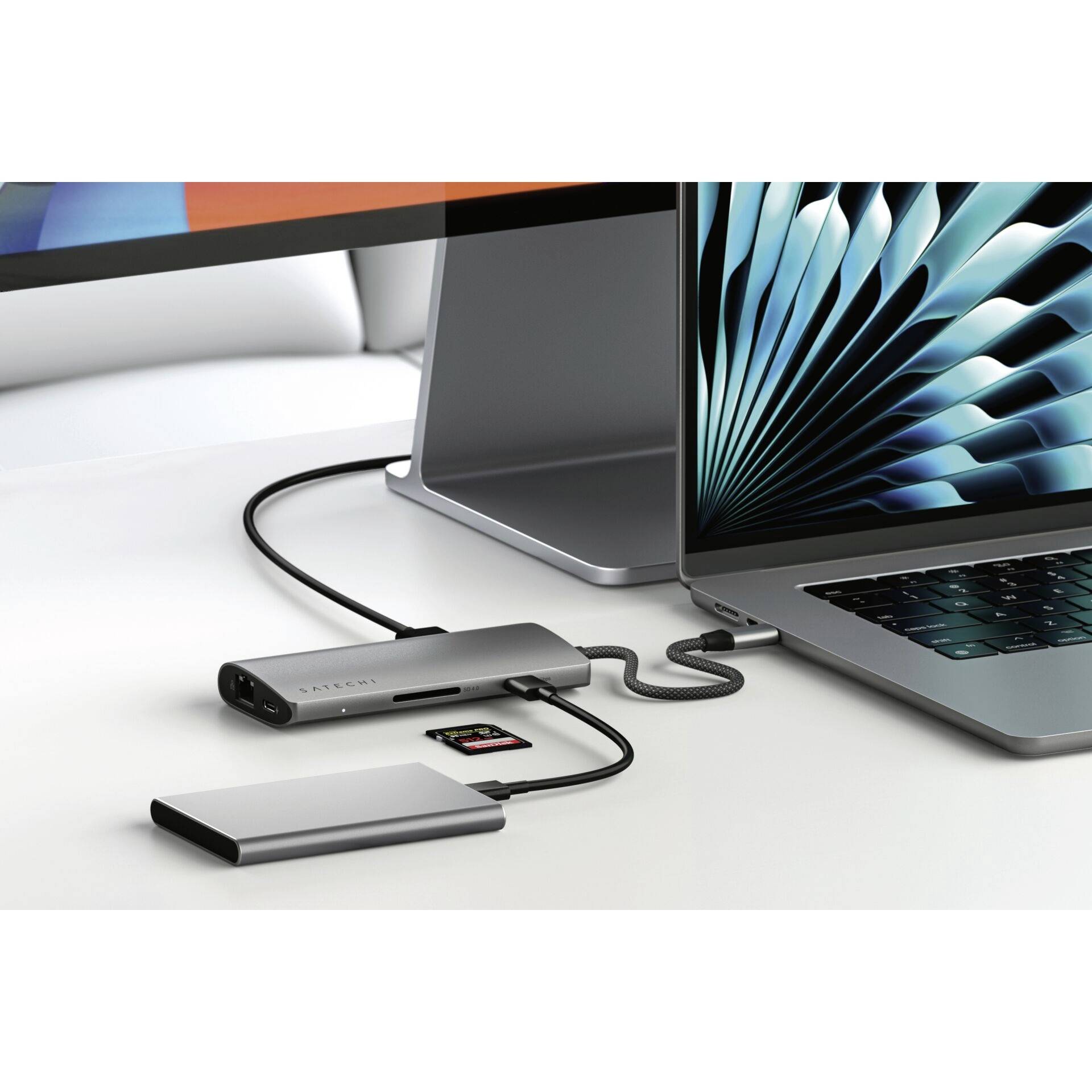 Notebook pripojené k externému zariadeniu pomocou kábla, vedľa ktorého leží úložné médium a pamäťová karta na stole.