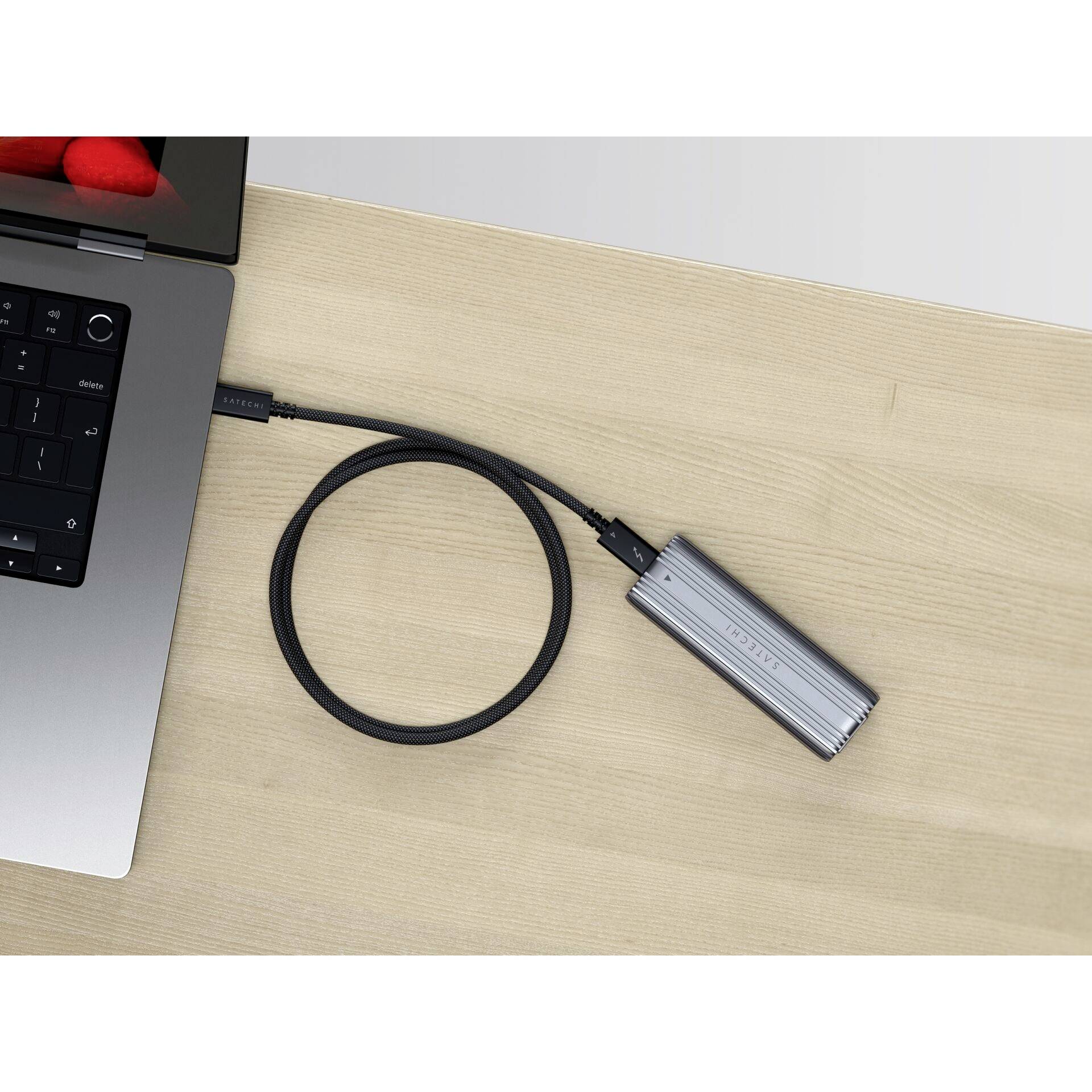 Externý pevný disk pripojený káblom k laptopu na drevenom stole.