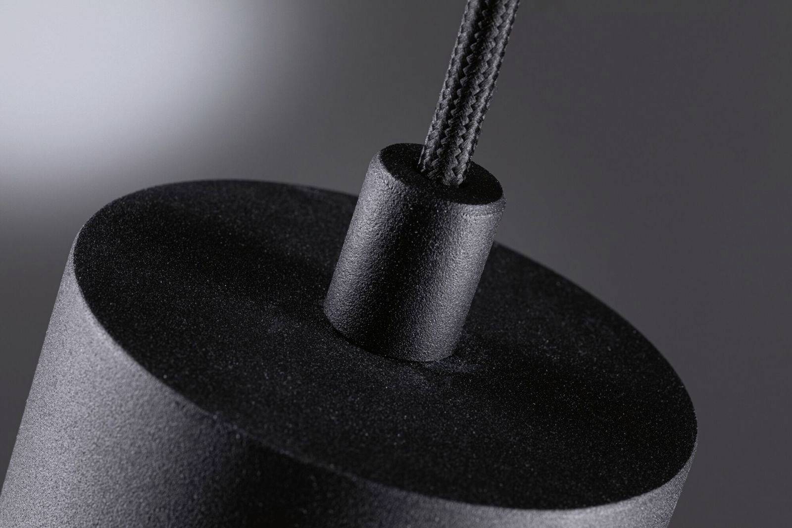 Detailný záber čiernej valcovej závesnej lampy s textilným káblom na šedom pozadí.