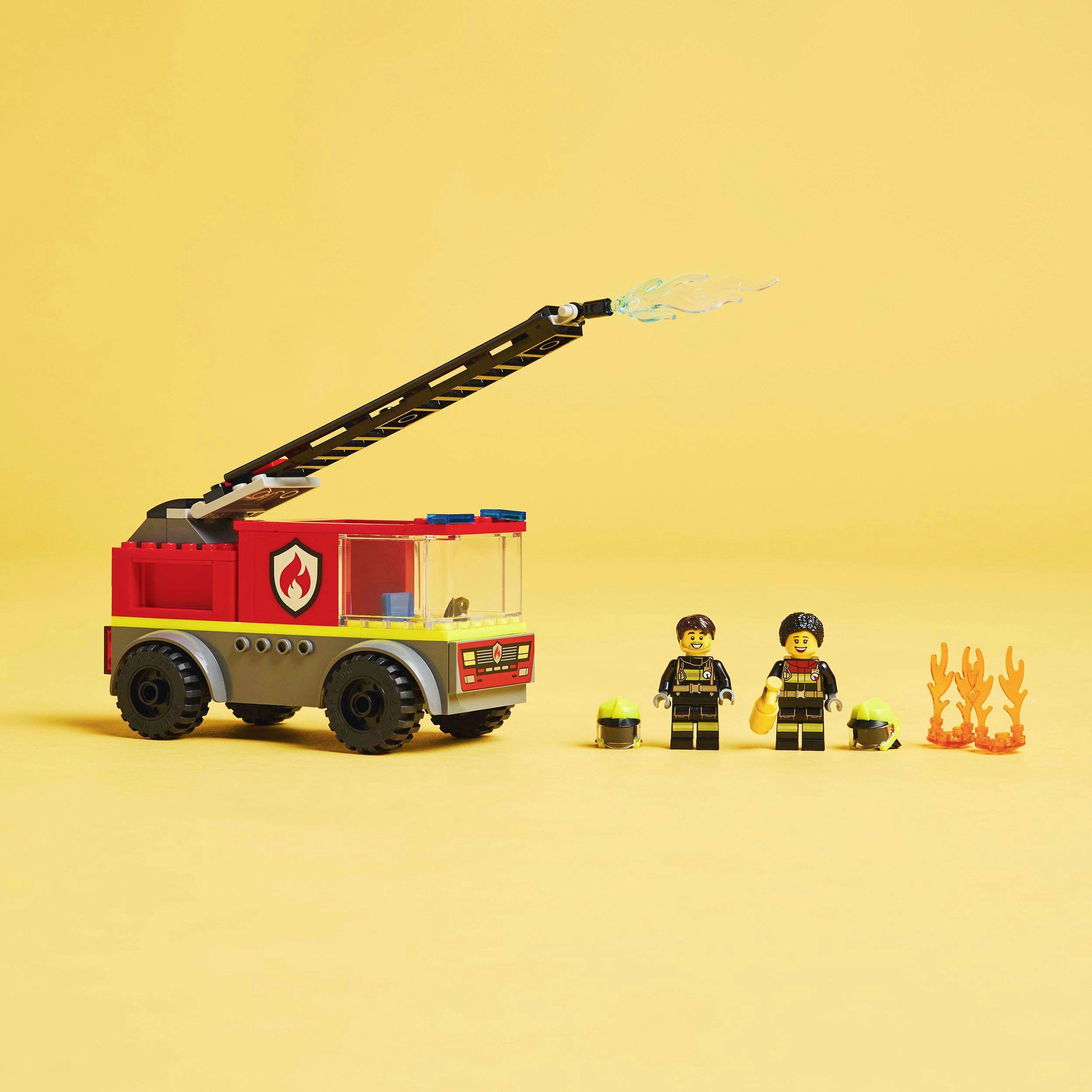 Hračkárske hasičské auto s výsuvným rebríkom a vodným spŕškaním, sprevádzané dvoma figúrkami v hasičských uniformách a plameňmi.