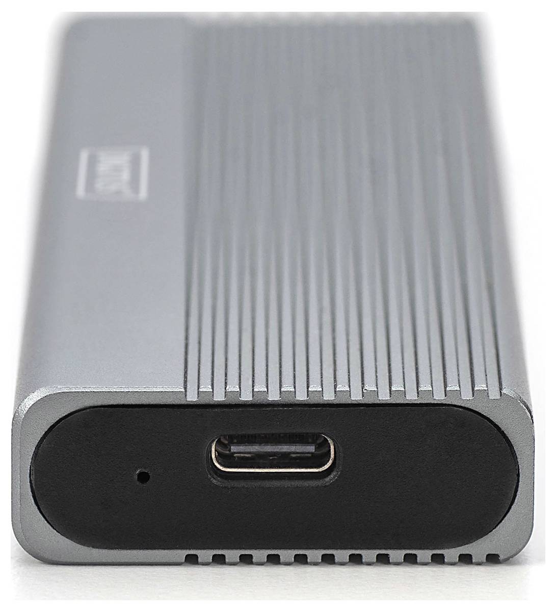 Strieborný externý pevný disk s USB-C portom na čiernom povrchu, s vertikálnymi drážkami na povrchu pre chladenie.