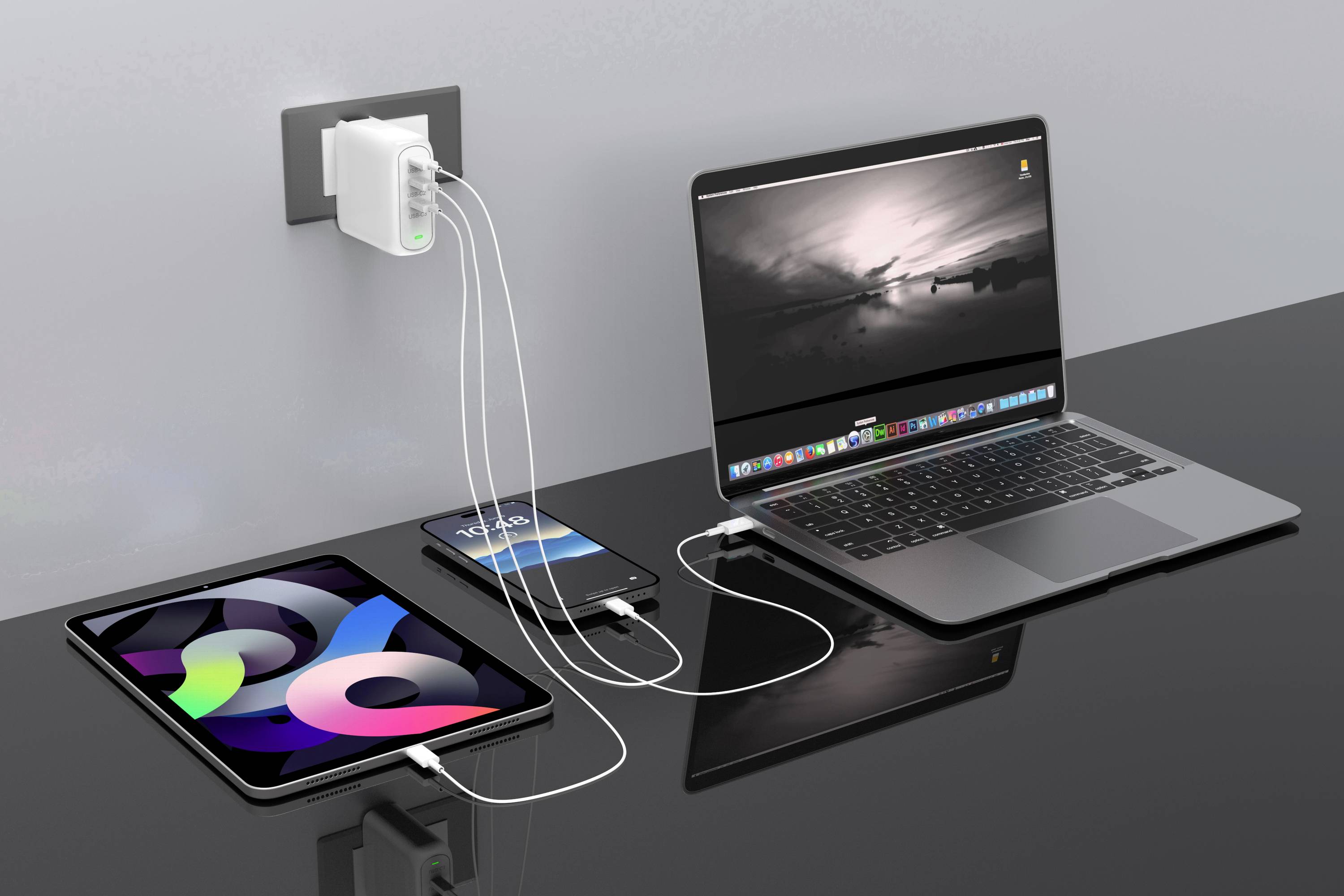 Tablet, smartfón a laptop sa nabíjajú cez nabíjačku zapojenú v stene. Všetky zariadenia sú prepojené káblami.