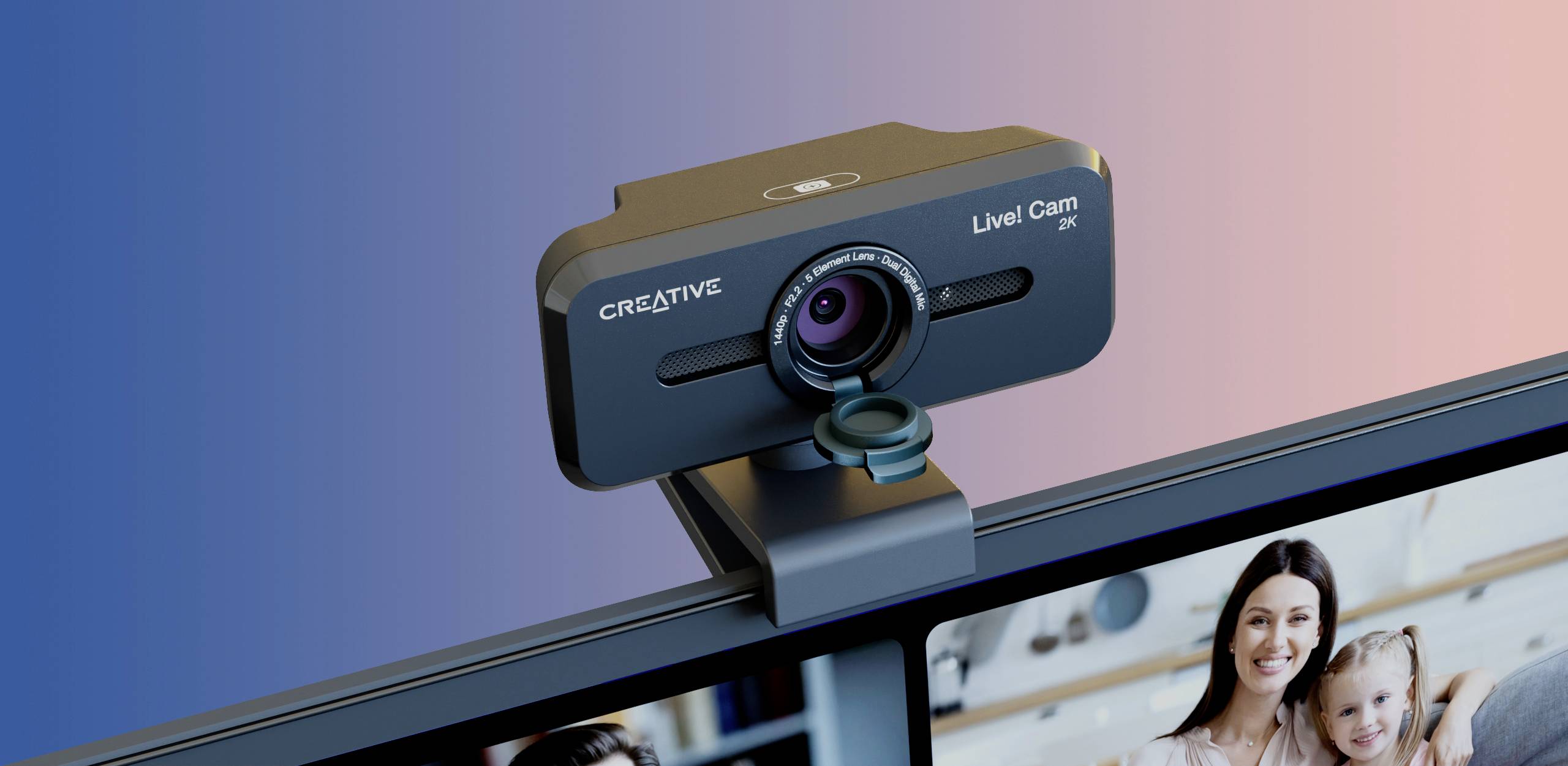 Webkamera značky Creative, model 'Live! Cam', namontovaná na monitore počítača. V pozadí rozmazané farebné prechody.