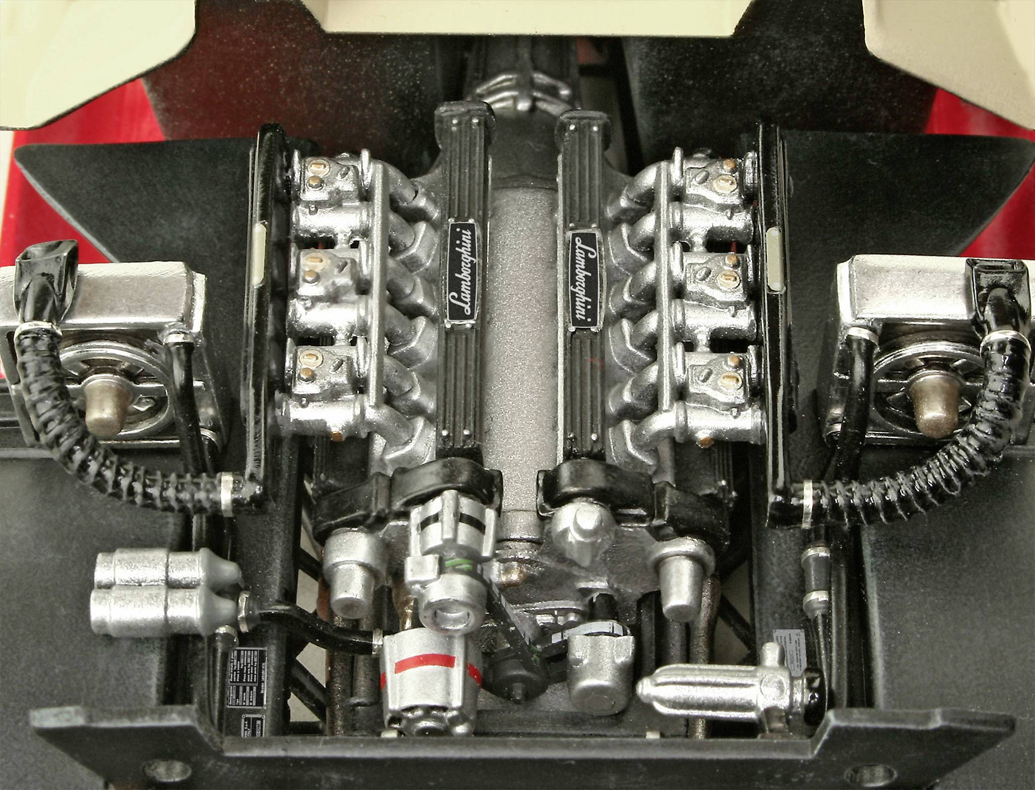 Model motora športového automobilu s detailnými piestami a ventilmi, označený nápisom 'Lamborghini'.