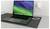 Otvorený laptop ležiaci na stole je pripojený do elektrickej zásuvky a zobrazuje zelený a modrý šetrič obrazovky.