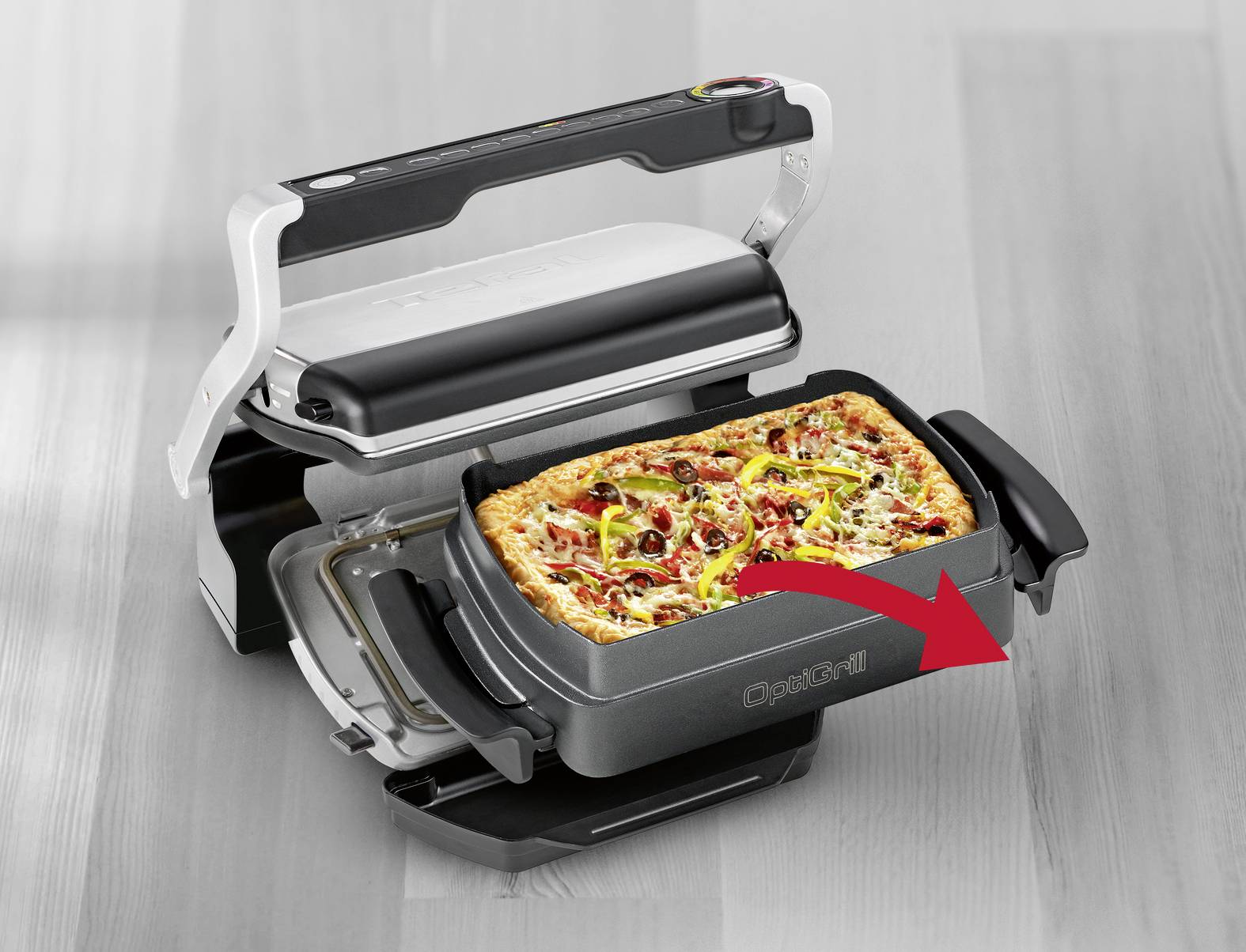 Malý elektrický gril s položenou pizzou. Červená šípka ukazuje, že grilovacia doska je vhodná na pizzu.