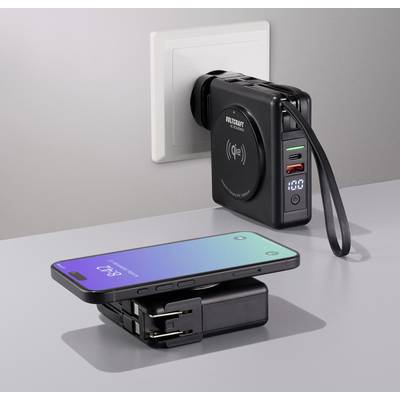 Nabíjačka v elektrickej zásuvke s USB portami a digitálnym displejom, ktorá bezdrôtovo nabíja smartfón na stole.