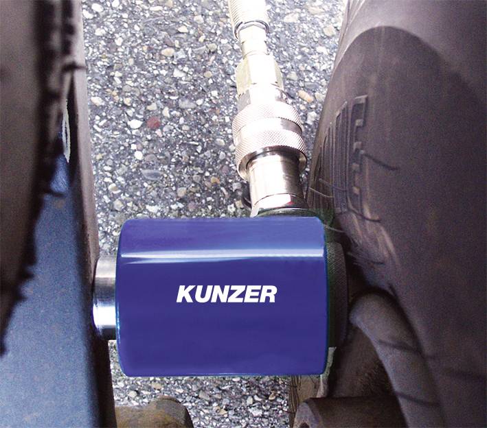 Na asfaltovej ploche je k pneumatike pripojené modré zariadenie od Kunzera, pravdepodobne na meranie tlaku vzduchu.