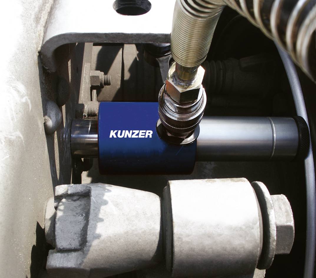 Hydraulický valec s modrým ochranným krytom a nápisom 'Kunzer' namontovaný v strojnej jednotke.