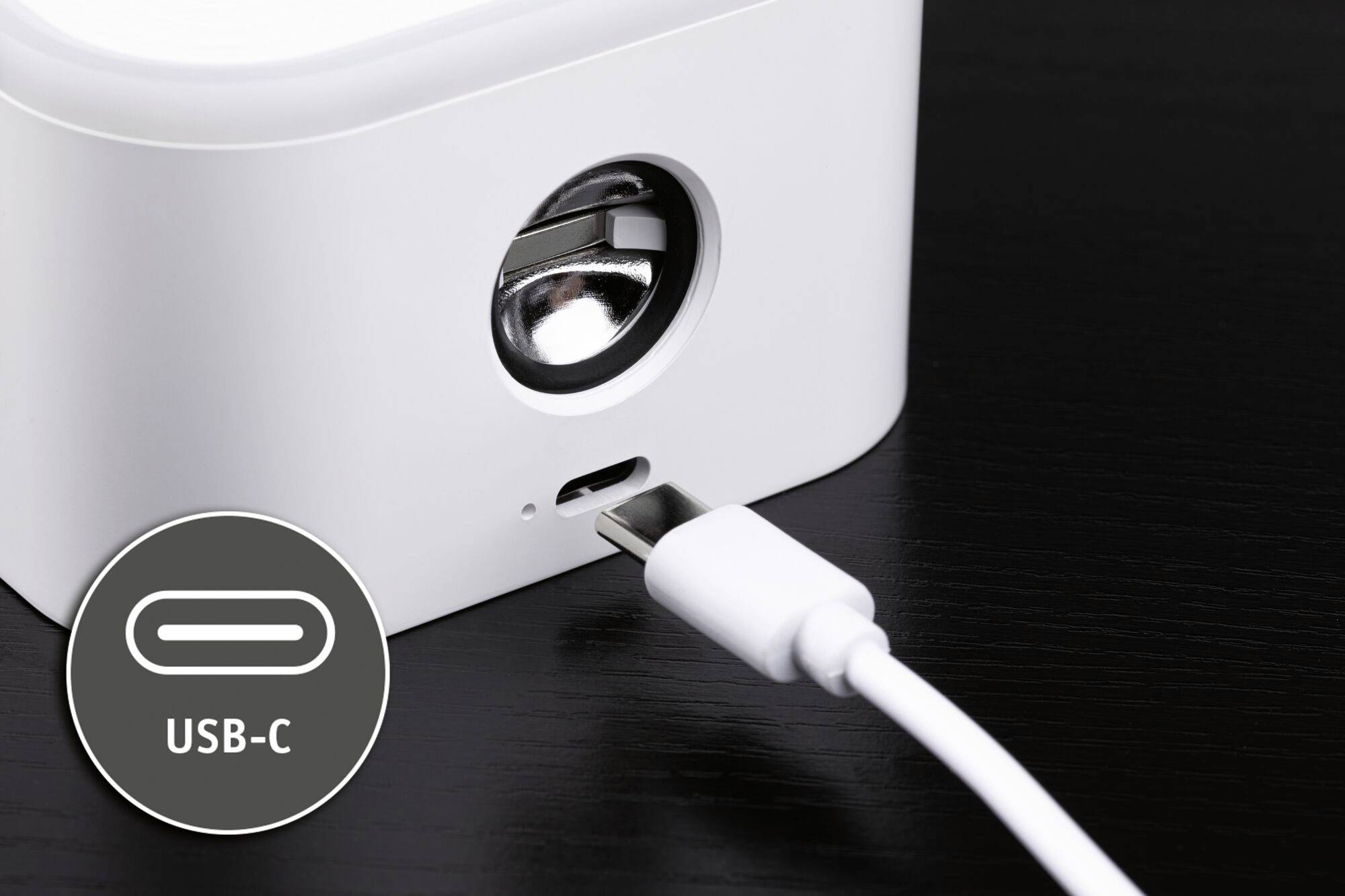 Biele zariadenie s okrúhlym otvorom a USB-C portom. USB-C kábel sa zasúva do zásuvky.