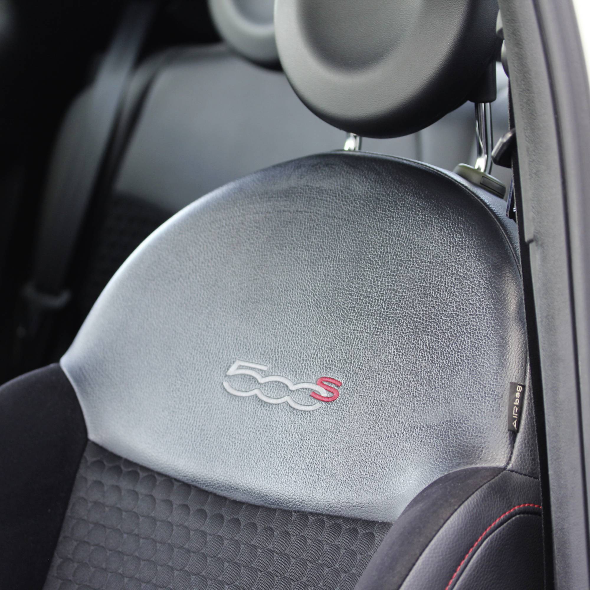 Sedadlo Fiat 500S s čiernym poťahom a vyrytým emblémom '500S' na operadle, pohľad zboku na sedadlo vozidla.