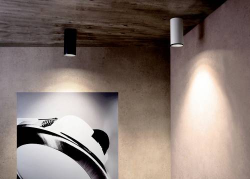 Umelecká galéria s dvoma stropnými svetlami, ktoré osvecujú čiernobielu fotografiu časti kamery.