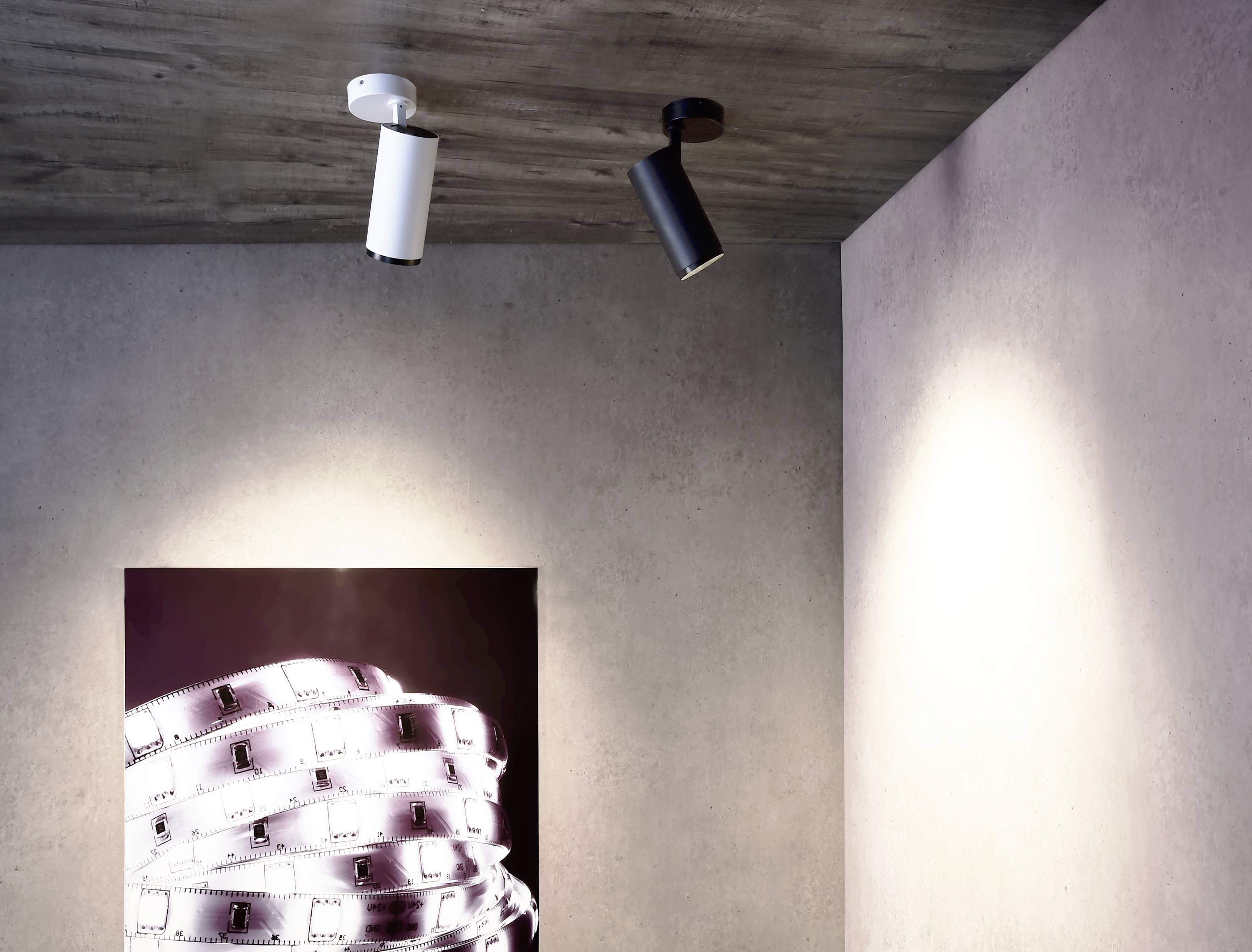 'Minimalistický priestor s dvoma stropnými svetlami a umeleckým dielom na stene zobrazujúcim filmové pásy.'