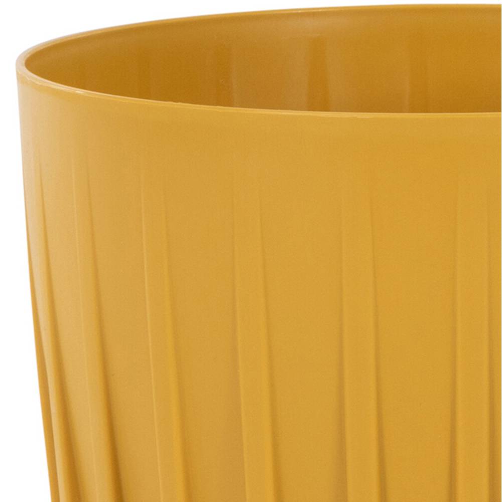 Oranžový, guľatý kvetináč z plastu so zvislými drážkami.