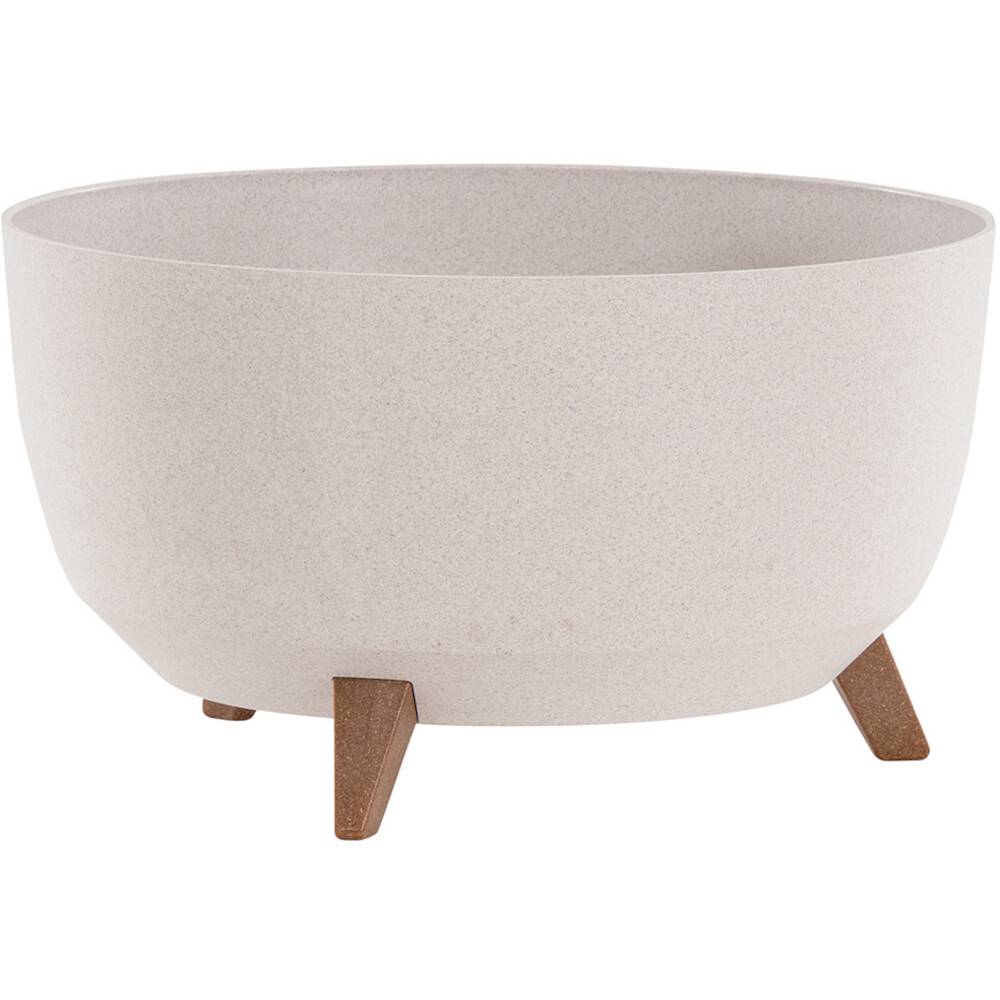 Veľký, okrúhly, krémový kvetináč z keramiky na troch krátkych drevených nohách. Minimalistický dizajn.