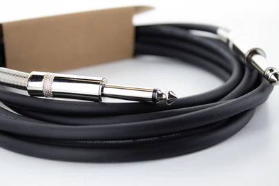 Čierne audiovlákno s dvoma striebornými 3,5mm jackami, stočené na bielom povrchu.