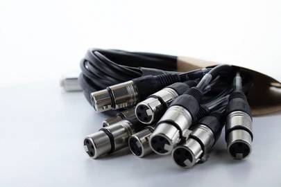 Niekoľko voľných XLR káblov leží pripravených na stole pre použitie v audio- alebo javiskej technike.