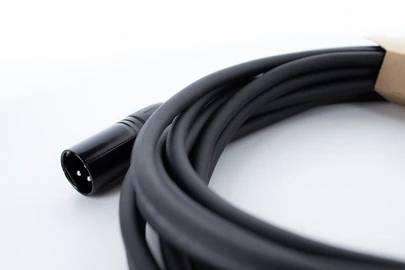 Čierny kábel s XLR konektorom, zvinutý do kruhu. Vhodný pre audio prepojenia v profesionálnych štúdiových aplikáciách.