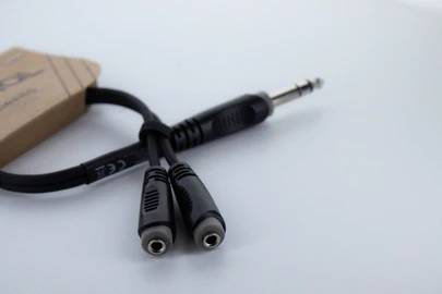 Audio adaptérový kábel s 6,3 mm stereo jack konektorom na dva 3,5 mm jacky. Viditeľný pravý horný roh obalu.