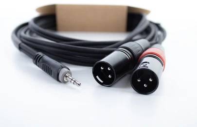 Na stole leží audio kábel s trojpólovým XLR konektorom na jednej strane a 3,5 mm jack zásuvkou na strane druhej.