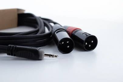 Na stole ležia dva XLR konektory a jeden 3,5 mm jack konektor, prepojené audiokáblom.