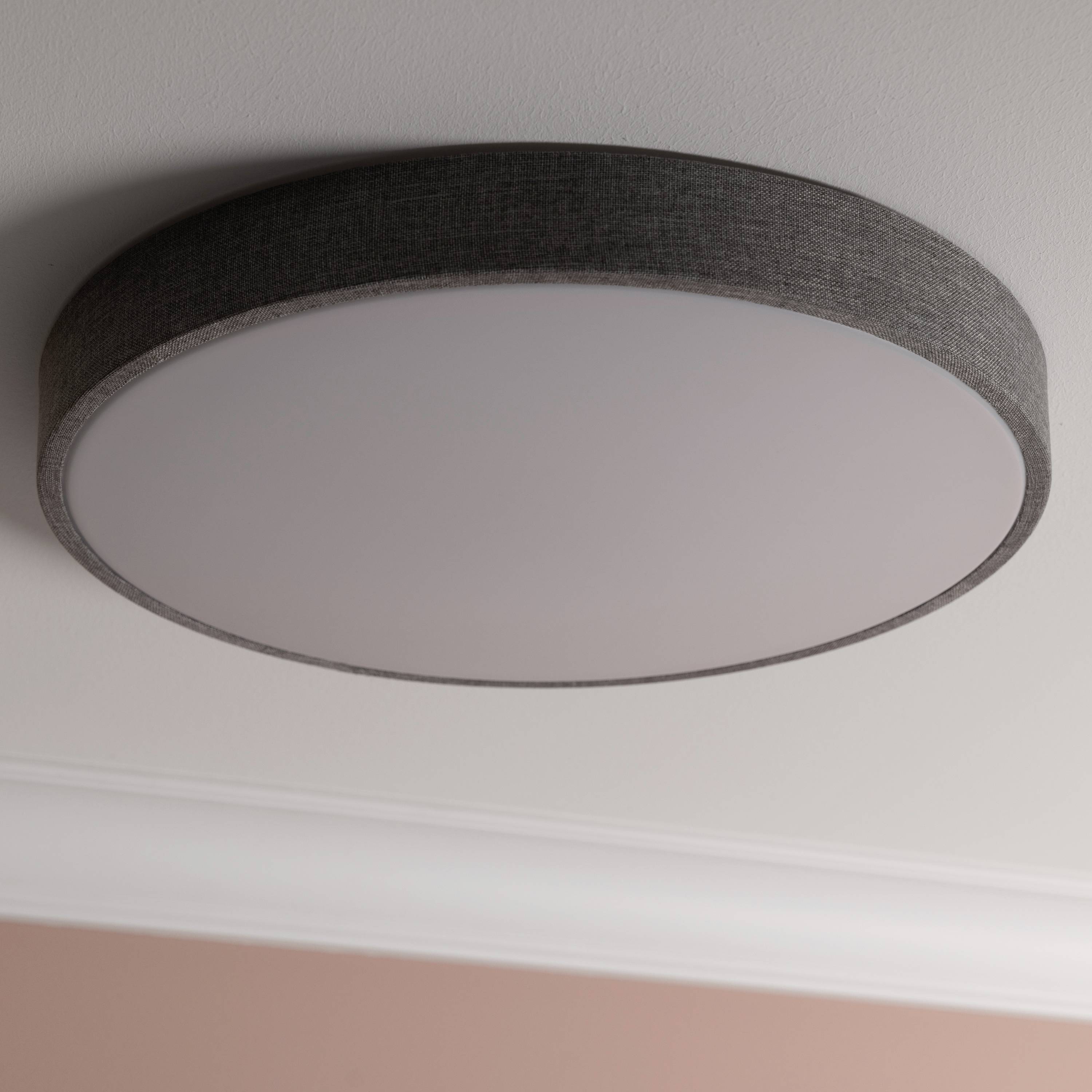 Plochý, okrúhly stropný svetlomet so sivým rámom na bielom strope. Rovnomerne osvetľuje a hodí sa k modernému interiéru.