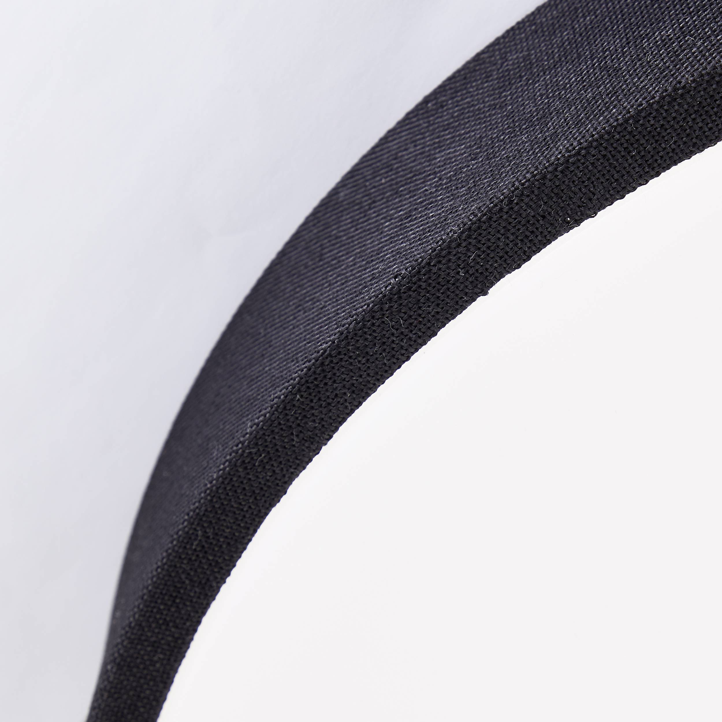 Čierny, guľatý objekt pred bielym pozadím, pravdepodobne detail nábytku alebo doplnku.