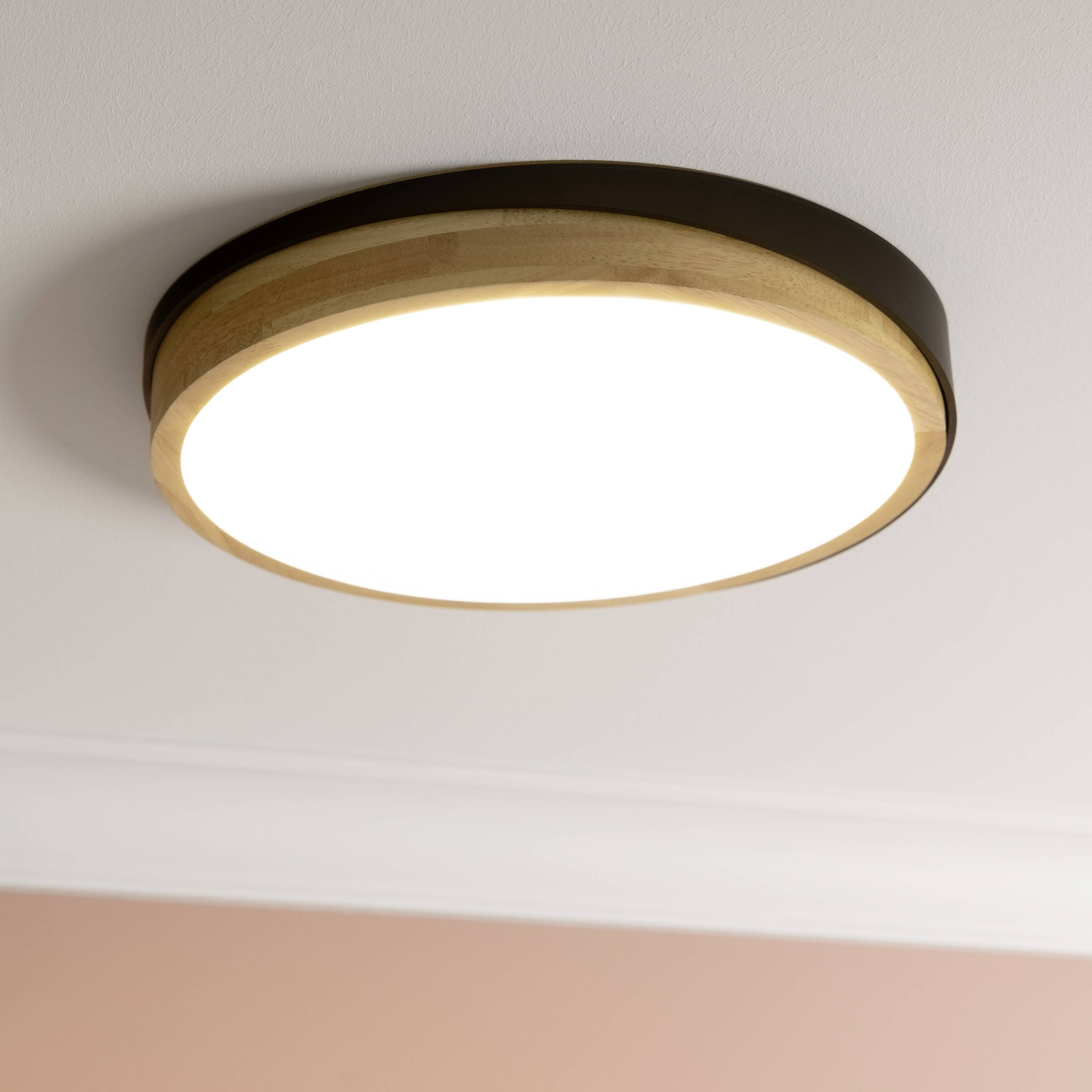 Okrúhle stropné svietidlo z dreva so svetlou LED-osvetlením, namontované na bielom strope, vytvára teplé, rovnomerné svetlo.