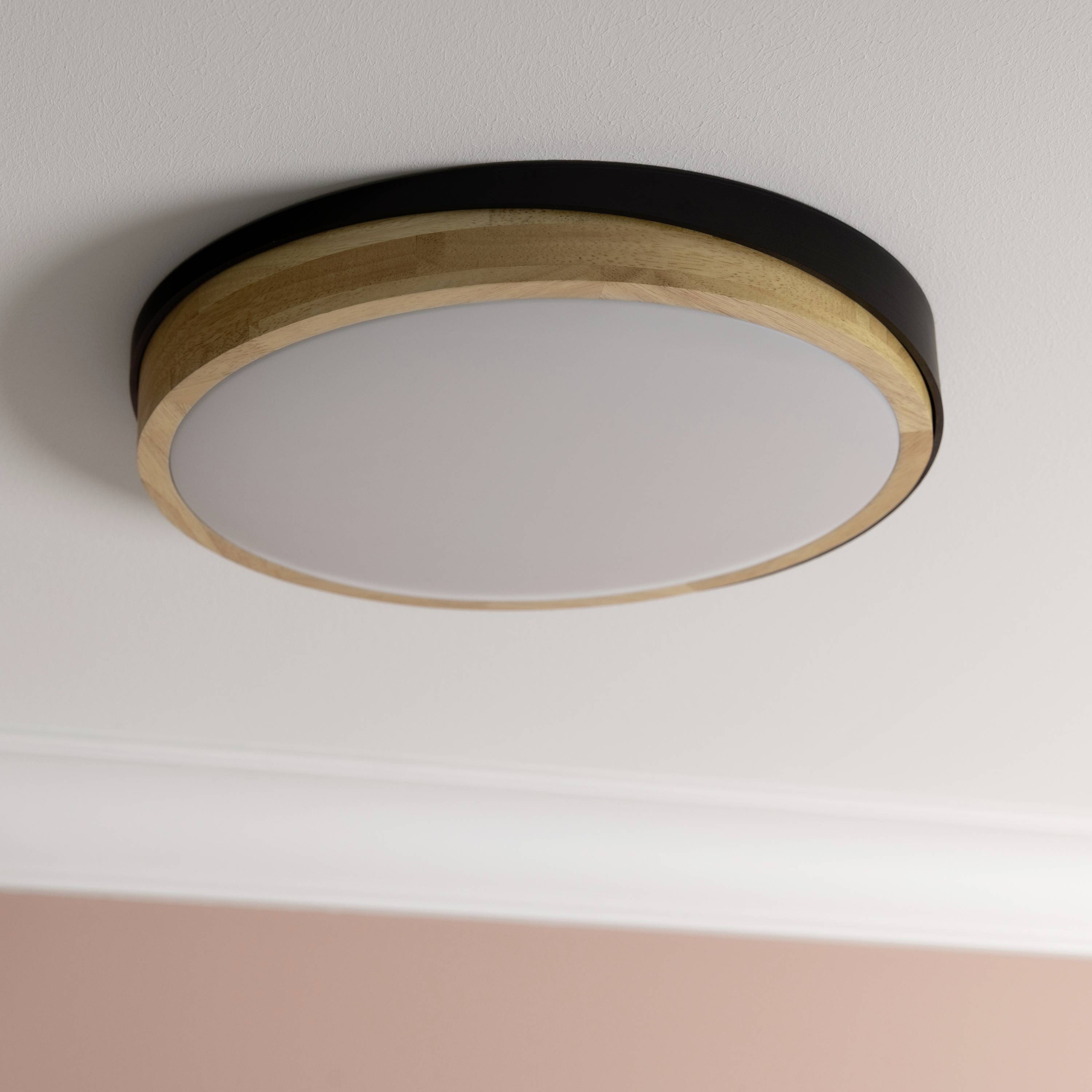 Okrúle stropné svietidlo s dreveným rámom namontované na ružovom strope.
