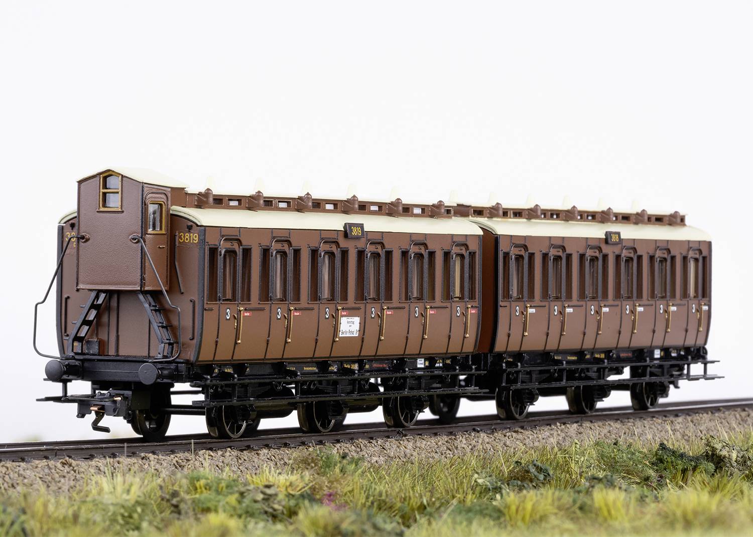 Hnedý historický železničný vagón na koľajniciach, modelová snímka. Vagón má detailne spracované okná a nápisy.