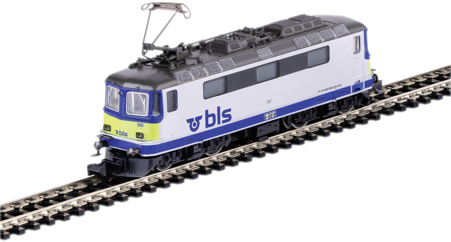 Modro-biely modelový vlak s nápisom 'BLS' jazdí po koľaji. Vlak má pantografickú štruktúru na odber elektrickej energie.