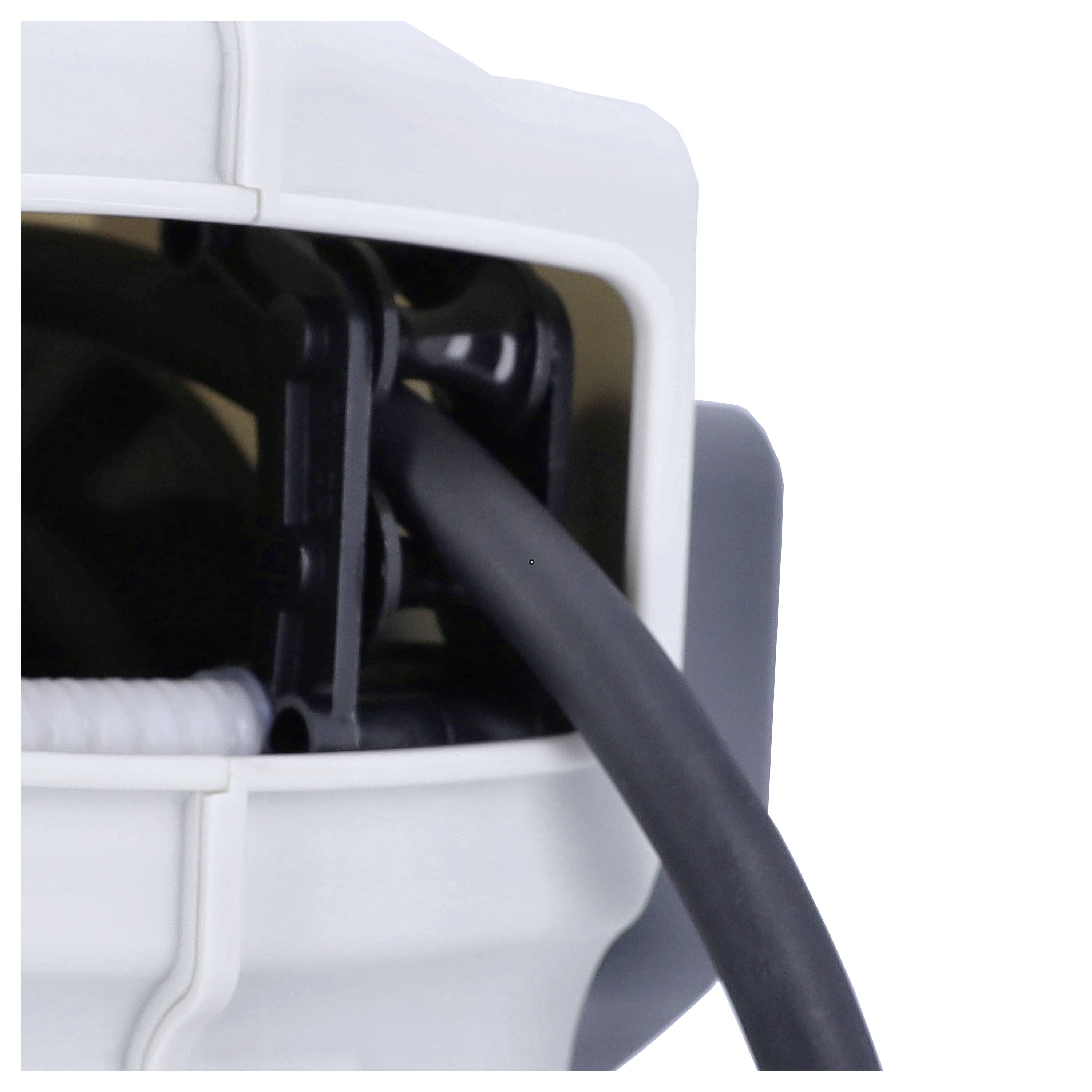 'Detail zblízka konektorového portu, kde je čierne elektrické vedenie zavedené do bielej plastovej prípojky.'