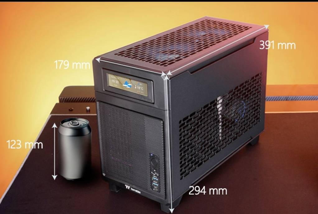 Čierna mini PC skrinka so mriežkovými bočnými stenami, vedľa nej plechovka nápoja. Rozmery: 391 mm x 179 mm x 294 mm.