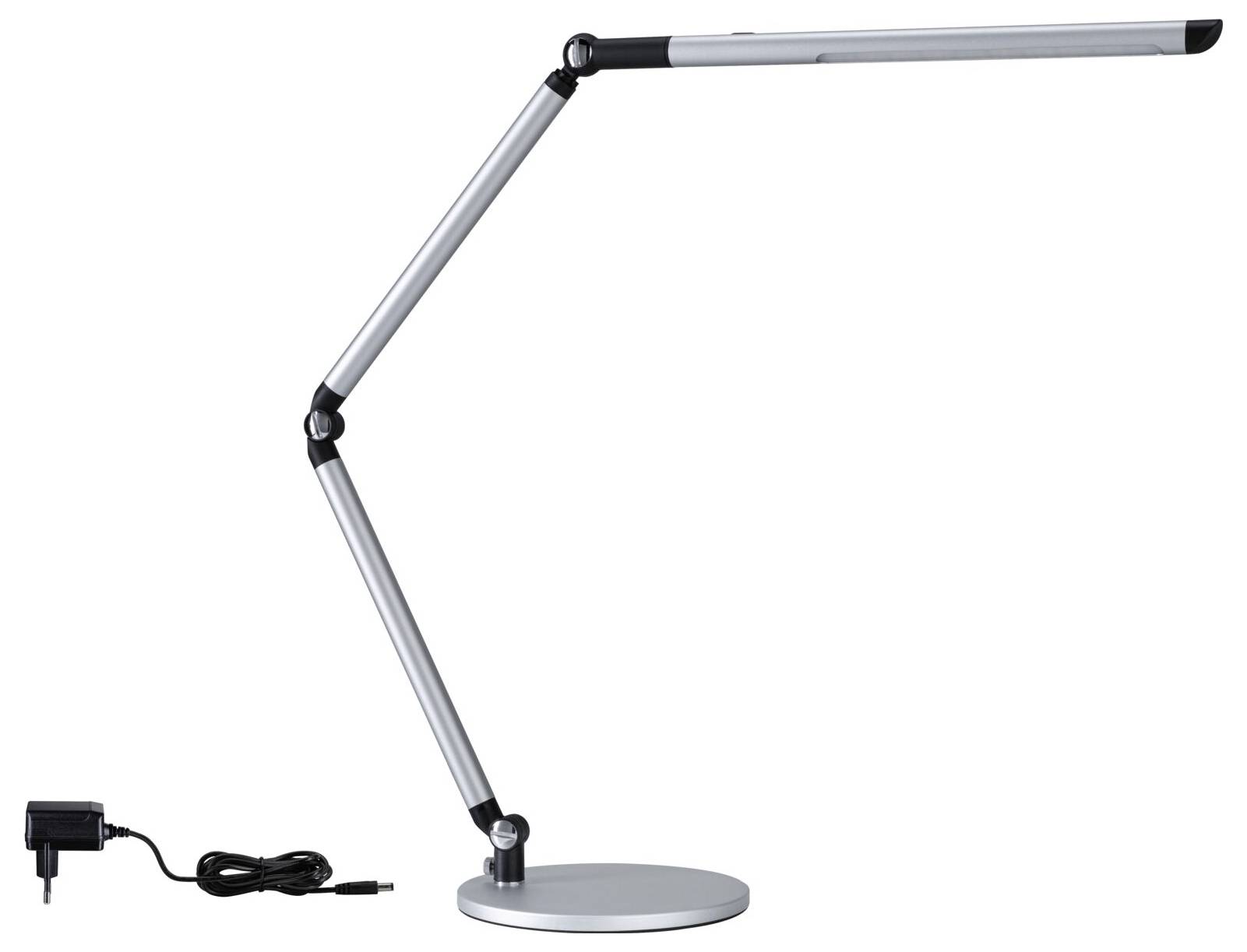 Strieborná stolná lampa s viacerými kĺbmi pre flexibilné nasmerovanie. Sieťový adaptér vľavo na obrázku.