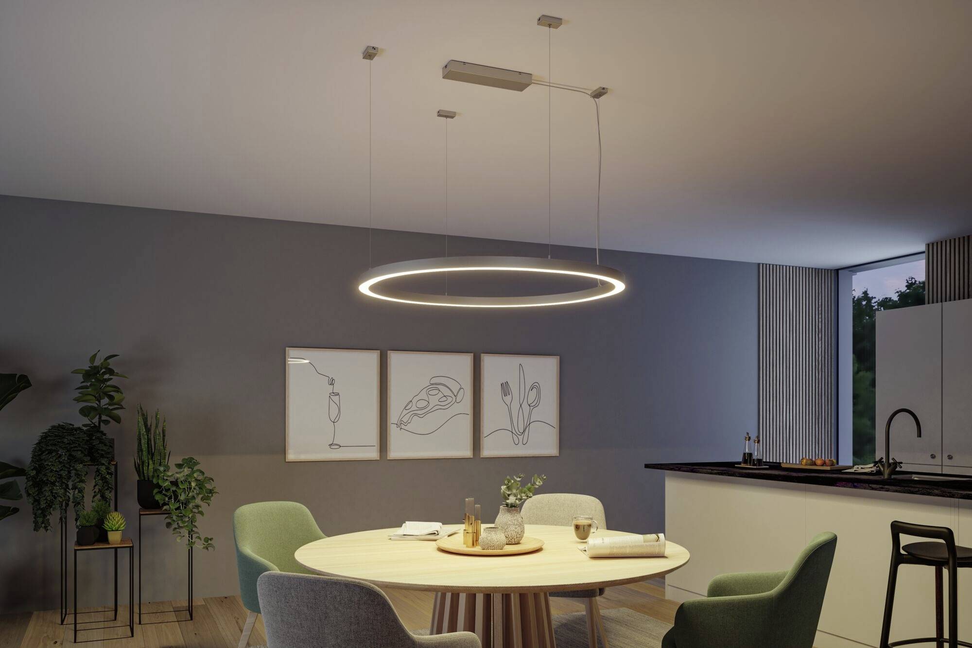 Moderná jedáleň s okrúhlym visiacim LED svietidlom nad dreveným stolom, obklopeným stoličkami. Na stene minimalistické umelecké diela.