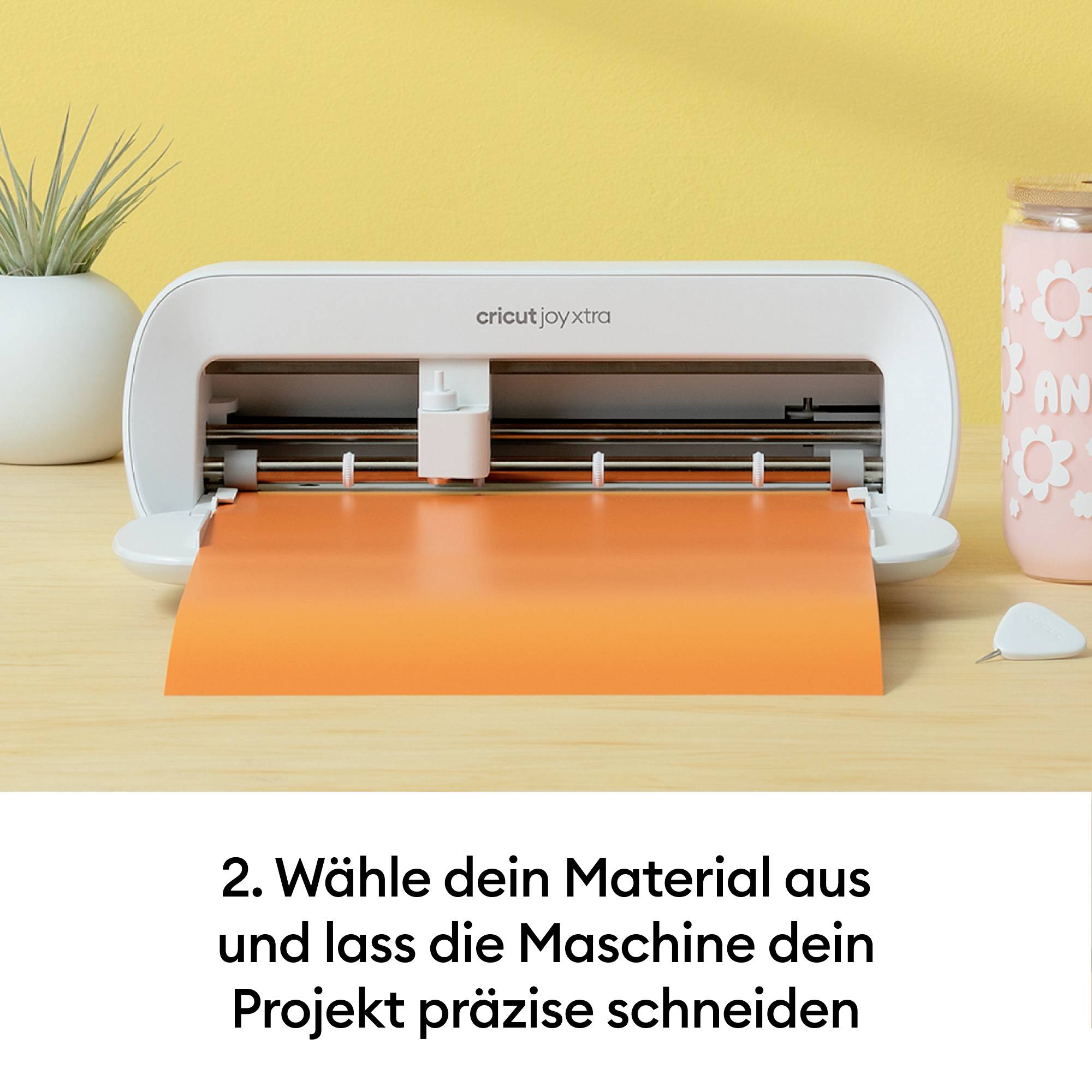 Rezačka vykrajuje oranžový papier. Text pod ním: '2. Vyber stroj a nechaj si svoj projekt presne vyrezať.'