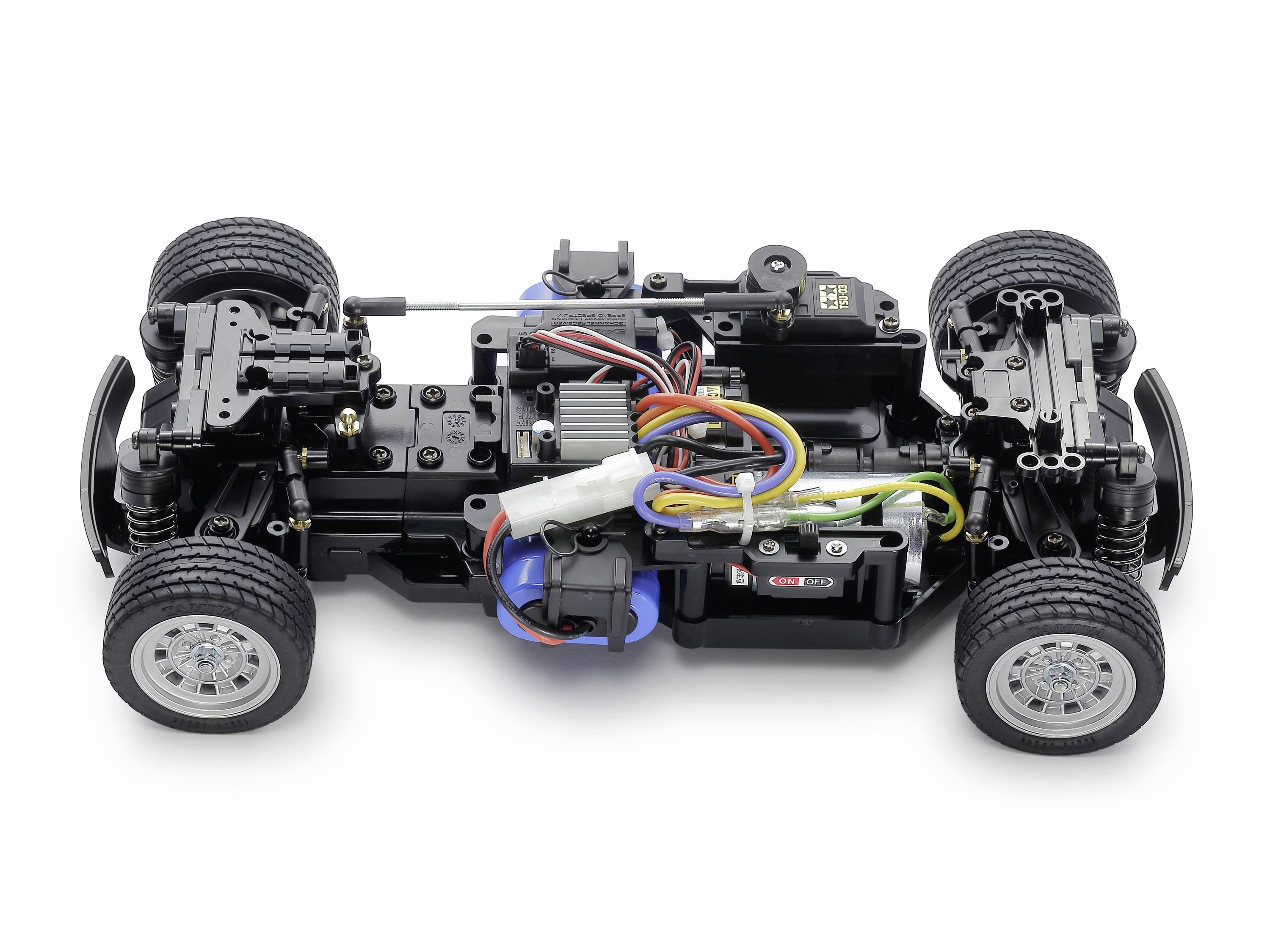 Diaľkovo ovládateľný automobilový podvozok so viditeľnými motormi a káblami, bez karosérie. Štyri kolesá sú namontované, technické detaily sú rozpoznateľné.