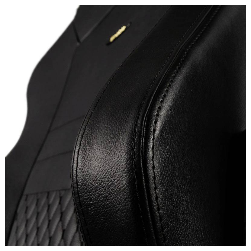 Detailný záber elegantného čierneho koženkového sedadla s jemným prešívaním a zlatým logom v ľavom hornom rohu.
