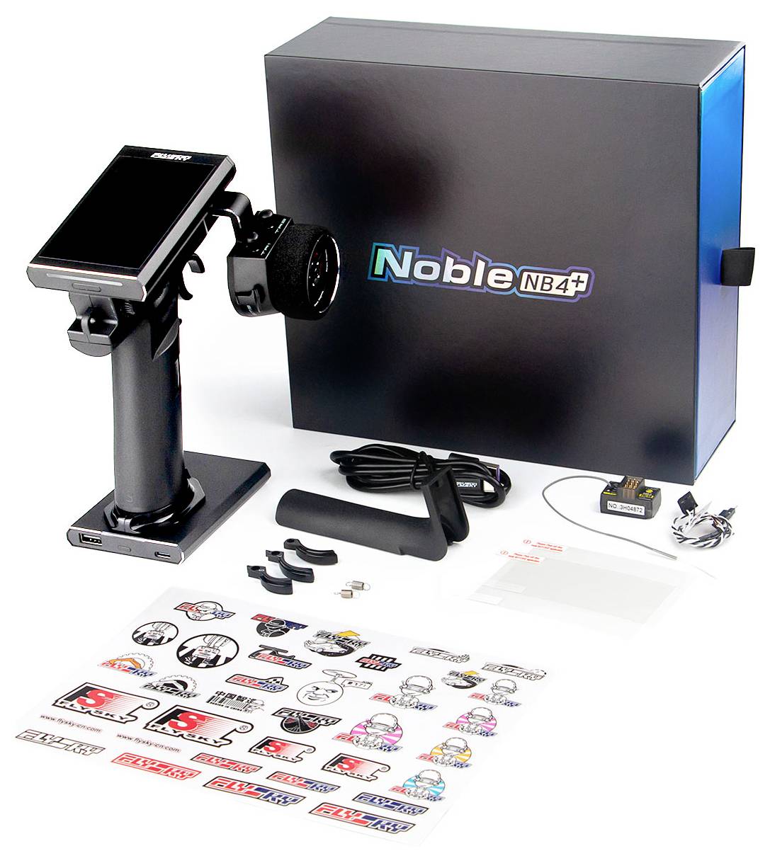 Sada diaľkového ovládania 'Noble NB4' so stolným ovládačom, prijímačom, nabíjačkou a nálepkami pred balením.