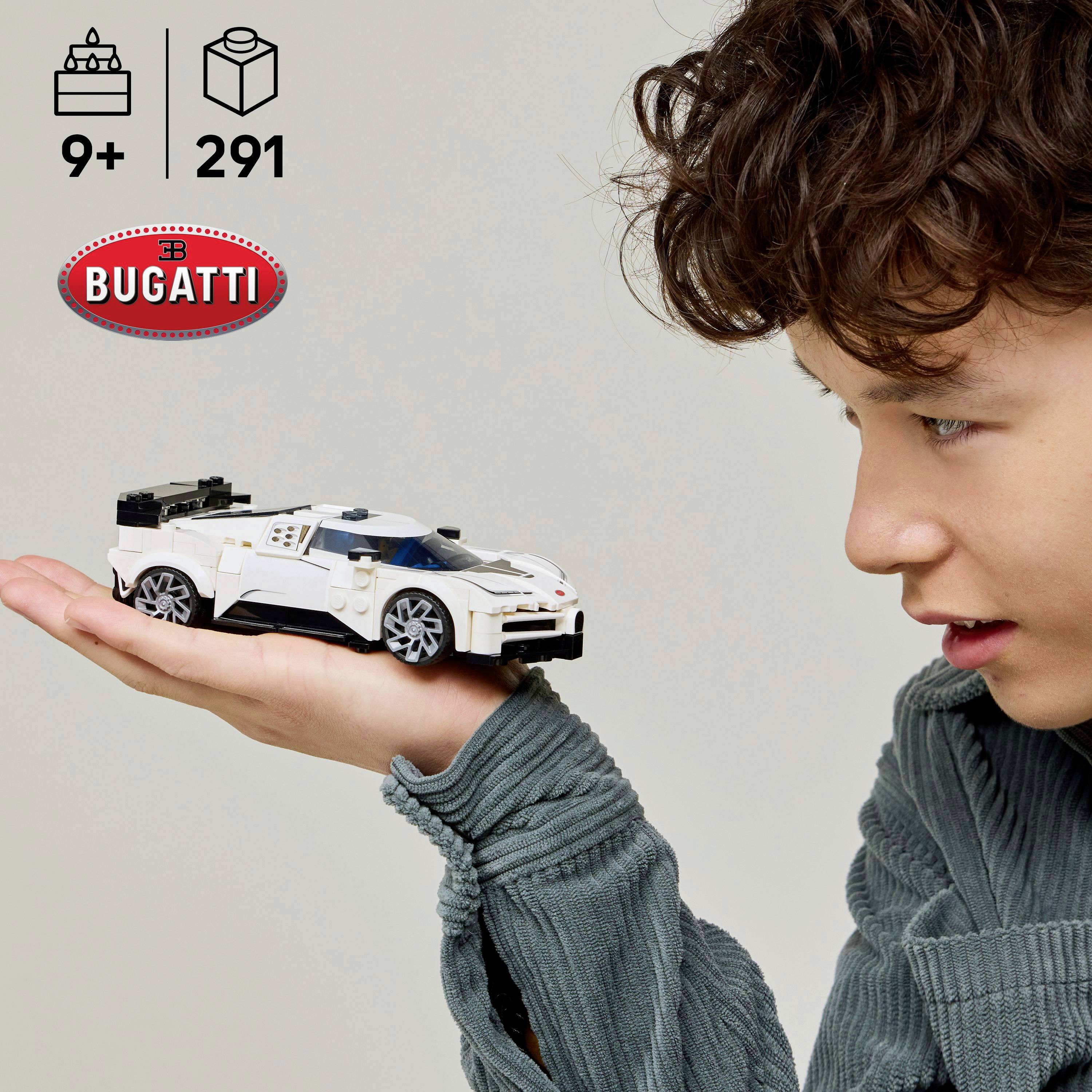 Dieťa drží biely model hračkárskeho pretekárskeho auta, ktorý sa podobá na Bugatti. Na škatuli je uvedené, že je určený pre deti od 9 rokov a obsahuje 291 dielov.