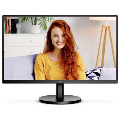 Usmiata žena s dlhými červenými vlasmi sedí na pohovke; v pozadí sú viditeľné rastlina a lampa.
