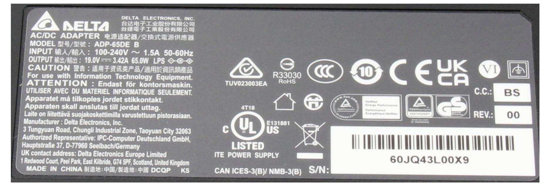 Etiketa napájacieho adaptéra Delta Electronics s modelovým číslom ADP-65DE B, vrátane vstupného a výstupného napätia, bezpečnostných certifikátov a výstražných upozornení.
