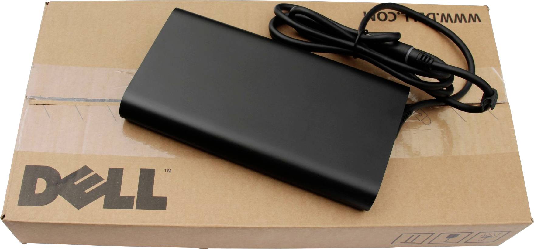 Čierny napájací adaptér pre notebook leží na čiastočne viditeľnej krabici Dell.