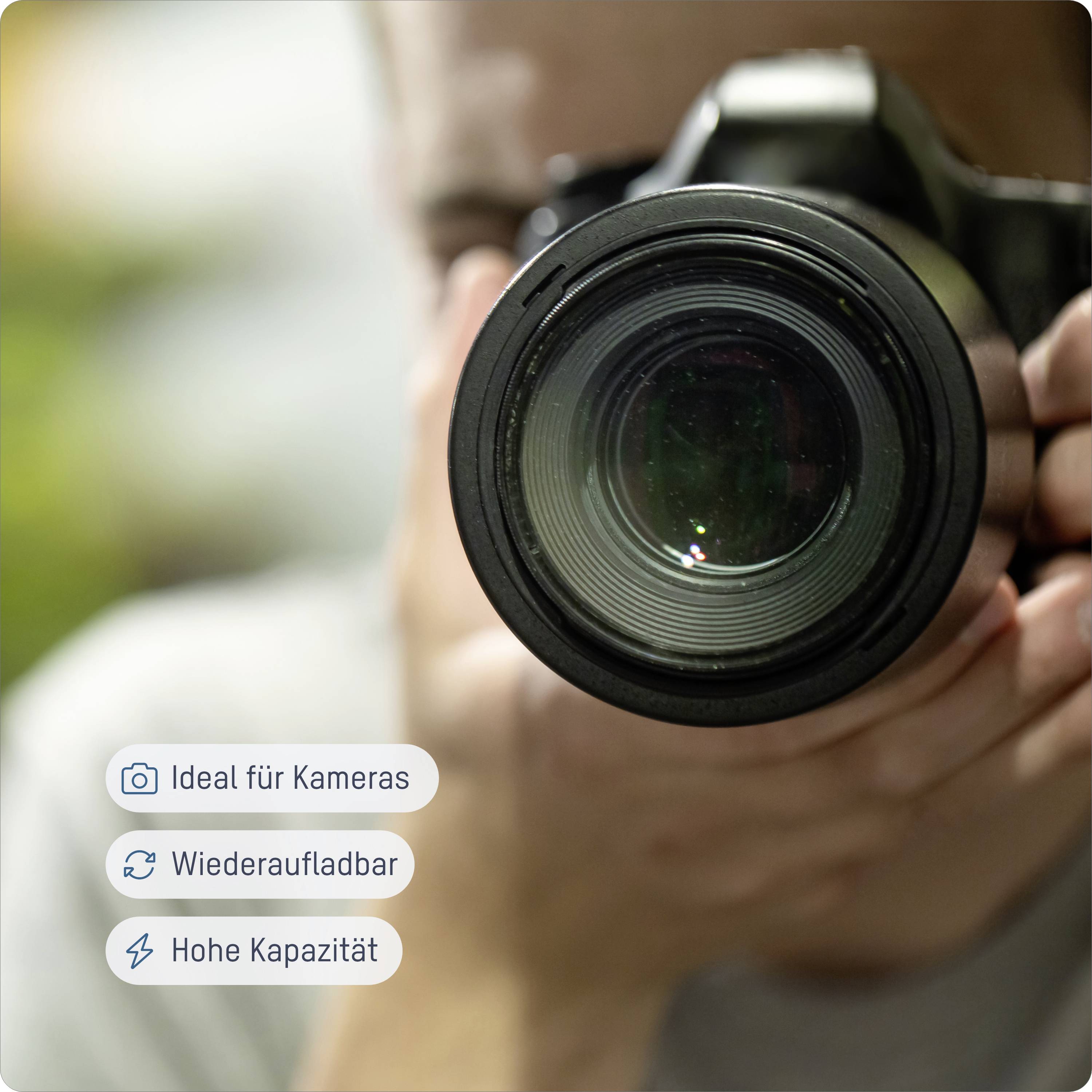 Osoba drží fotoaparát, pričom fokus je zameraný na objektív fotoaparátu. Vľavo sa zobrazujú symboly s vlastnosťami produktu: 'Ideálny pre fotoaparáty', 'Nabíjateľný', 'Vysoká kapacita'.
