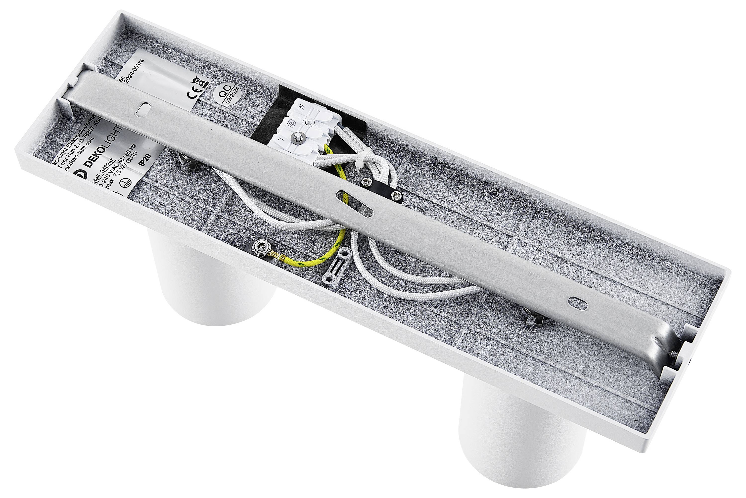 Kovový komponent s káblami a elektronickými súčiastkami na sivej základni, používaný pre technické alebo elektrické inštalácie.