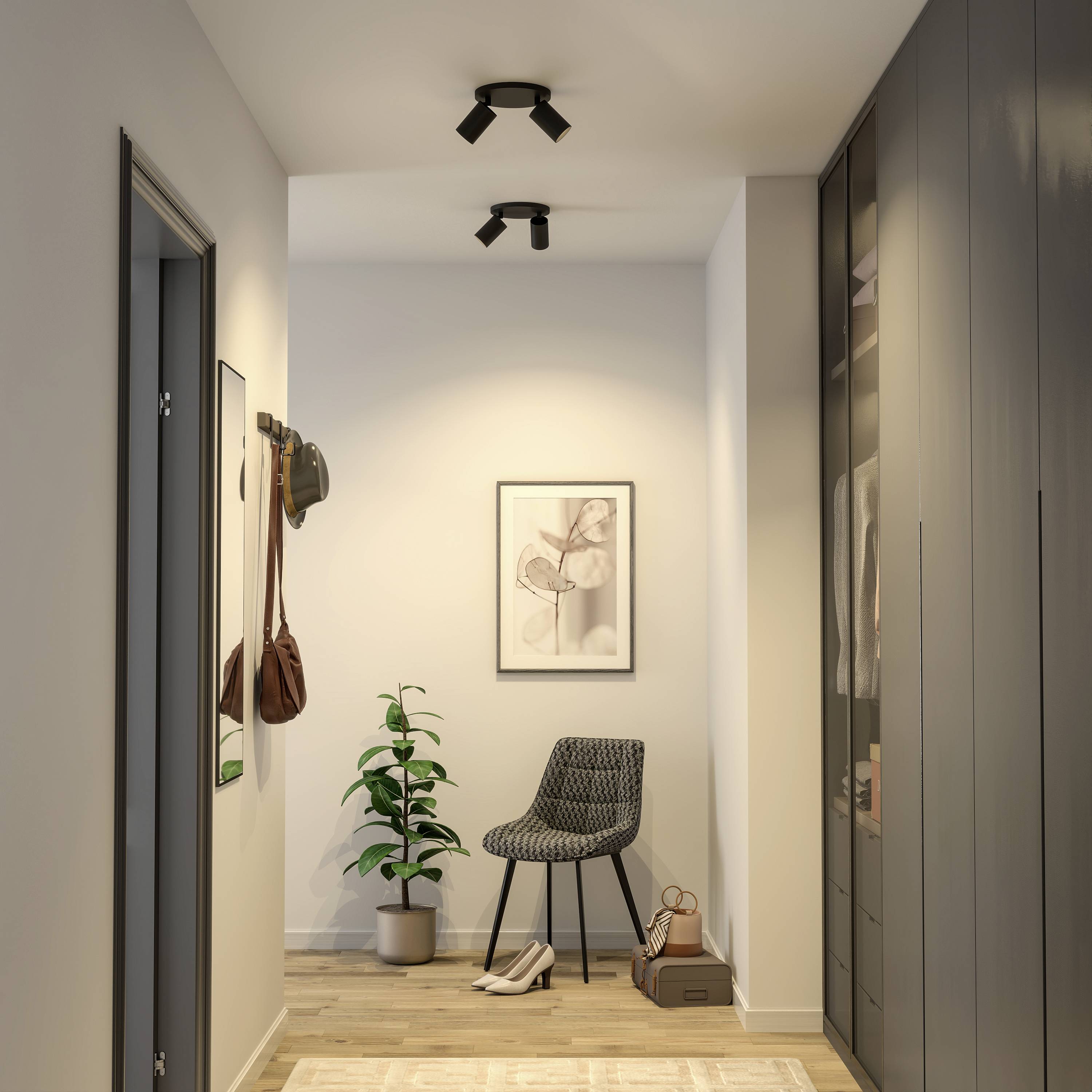 Chodba so stoličkou, kvetináčom a obrazom na stene. Moderný dizajn s teplým svetlom, na stene visí taška na háčiku.